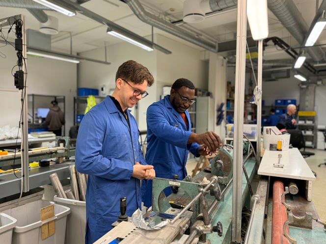 Fredrik and Jacob are wearing blue lab coats. In the background you can see typical lab equipment.